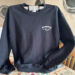 Black sweatshirt with seafood logo hanging up