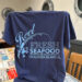 Navy t-shirt advertising Reel Fresh Seafood restaurant.