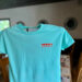 Turquoise shirt with Stewby's Seafood Shanty logo.