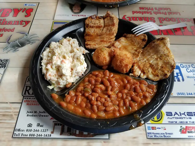 Grilled chicken, baked beans, and coleslaw on plate.