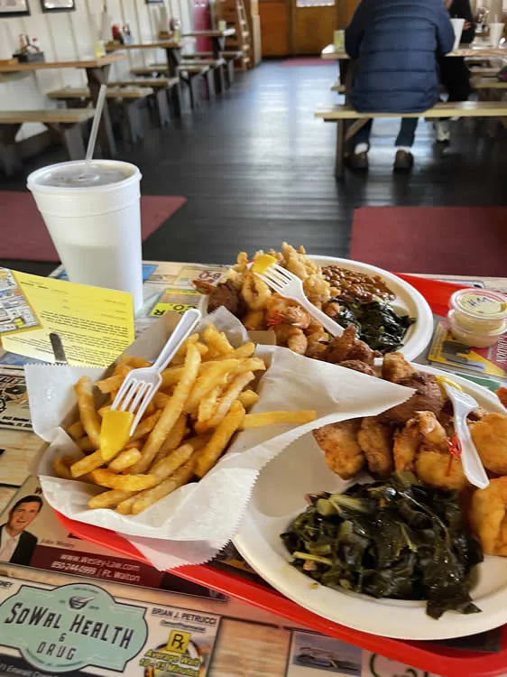 Fried seafood platter with fries and greens in diner.