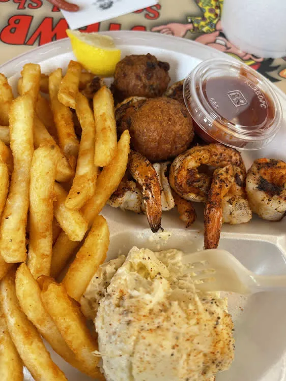 Fried shrimp with fries, hushpuppies, coleslaw, lemon garnish.