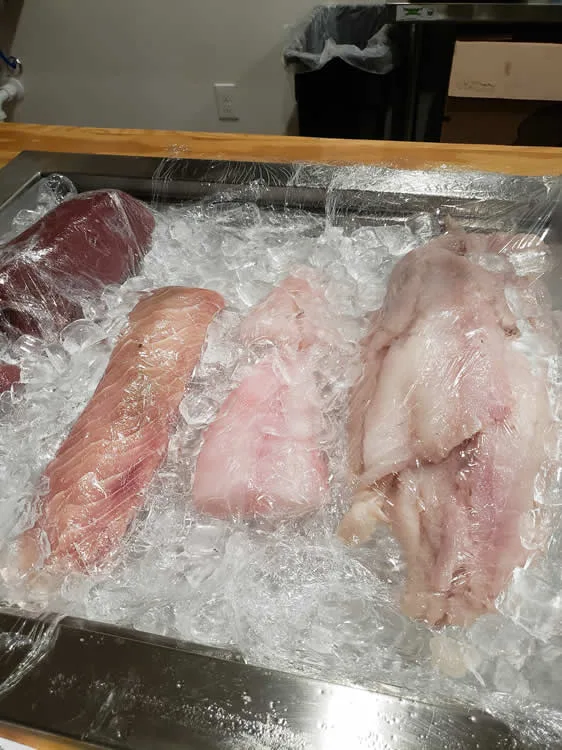 Assorted fish fillets on ice display.