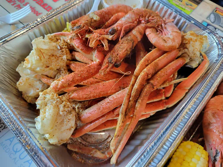 Seafood boil with crab legs and shrimp in tray.