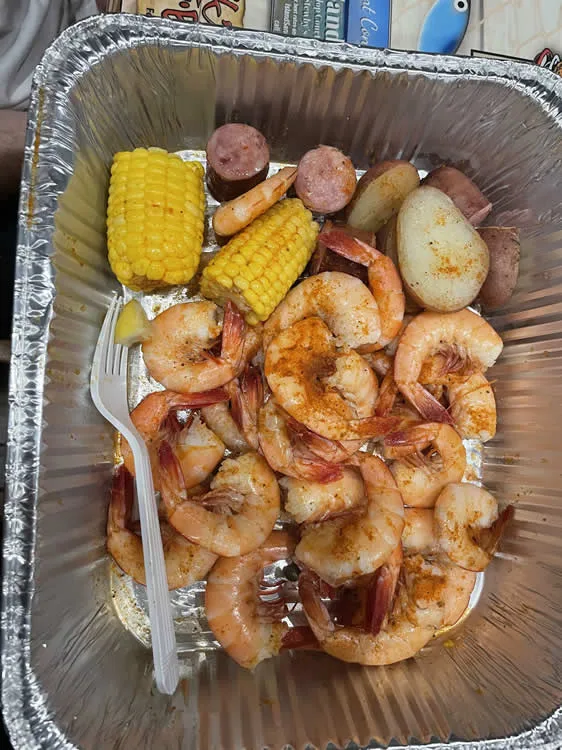 Shrimp boil with corn, sausage, potatoes in tray.