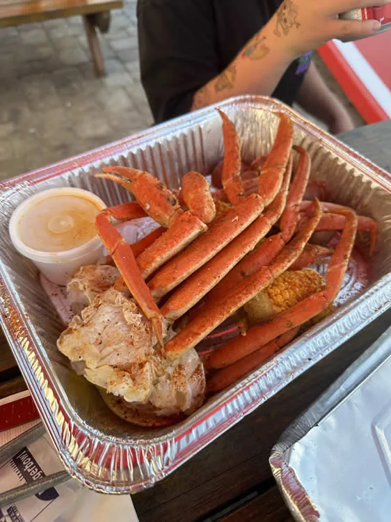 Steamed crab legs with corn and butter in tray.