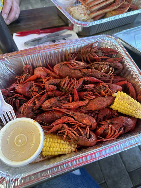 Tray of boiled crawfish with corn and sauce.